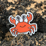 Crab sticker on sandy ocean rocks